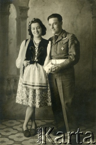 1945, Dicomano, Włochy.
Silvia Szymula z domu Valli i Stefan Szymula. S. Szymula przed wojną pracował w Powiatowym Zarządzie Drogowym w Buczaczu, po 1939 ukrywał się. Aresztowany po nieudanej ucieczce do Rumunii, osadzony w więzieniu w Czortkowie, później w Starobielsku. Skazany na 5 lat obozu, zesłany w styczniu 1941 roku na Syberię. Dostał się do Armii Andersa, z którą został ewakuowany do Iranu. Przeszedł z nią cały szlak bliskowschodni. W Palestynie ukończył Szkołę Podchorążych Piechoty Rezerwy i został mianowany porucznikiem. Walczył pod Monte Cassino. W 1948 roku emigrował z żoną i synkiem do Argentyny. Nz. Silvia w stroju ludowym stylizowanym na polski, który sama uszyła.
Fot. NN, zbiory Silvii Szymuli, reprodukcje cyfrowe w  Bibliotece Polskiej im. Ignacego Domeyki w Buenos Aires (Biblioteca Polaca Ignacio Domeyko) i w Ośrodku KARTA w Warszawie