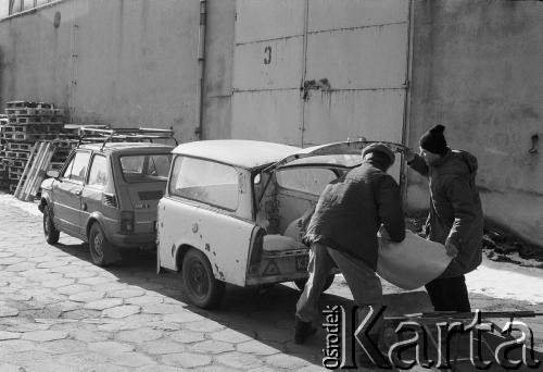 1987, Ostrzeszów, woj. kaliskie, Polska. 
Mężczyźni wkładający worek do przyczepki - samochodu.
Fot. Stanisław Kulawiak, zbiory Ośrodka KARTA.