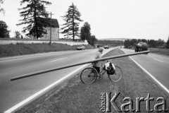 1988, Siewierz, Polska.
Droga krajowa nr 1, kobieta z rurą na rowerze.
Fot. Stanisław Kulawiak, zbiory Ośrodka KARTA.