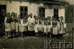 Przed 1939, brak miejsca.
Zdjęcie grupowe dziewcząt w strojach ludowych z księdzem. Fotografia z rodzinnego archiwum Zofii Hurko.
Fot. NN, zbiory Archiwum Historii Mówionej Ośrodka KARTA i Domu Spotkań z Historią, udostępniła Zofia Hurko w ramach projektu 