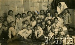Ok. 1939, Brzeżany, woj. tarnopolskie, Polska.
Zdjęcie grupowe dzieci w przedszkolu. Teresa Luszniak siedzi druga z prawej (w kokardzie), a brat Zygmunt stoi obok siostry zakonnej, po lewej stronie.
Fot. NN, zbiory Archiwum Historii Mówionej Ośrodka KARTA i Domu Spotkań z Historią, udostępniła Teresa Luszniak w ramach projektu 