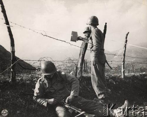 Wiosna 1944, rejon Monte Cassino, Włochy.
Bitwa pod Monte Cassino. Dwaj amerykańscy żołnierze przy ogrodzeniu z drutu kolczastego, na którym wisi kartka: 