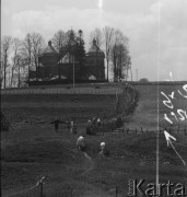 1951-1952, Bystre, Bieszczady, Polska.
Turyści zmierzają do cerkwi greckokatolickiej pw. św. Michała Archanioła. Budynek cerkwi powstał w latach 1901-1902. Greckokatolicka cerkiew była filią w Michniowcu. Została opuszczona w roku 1951, kiedy tereny te wróciły do Polski w ramach wymiany z ZSRR. Przez krótki czas mieszkańcy użytkowali ją jako kościół rzymskokatolicki. Nie zaakceptowały tego ówczesne władze i obiekt został zamknięty.
 Fot. Jerzy Konrad Maciejewski, zbiory Ośrodka KARTA.